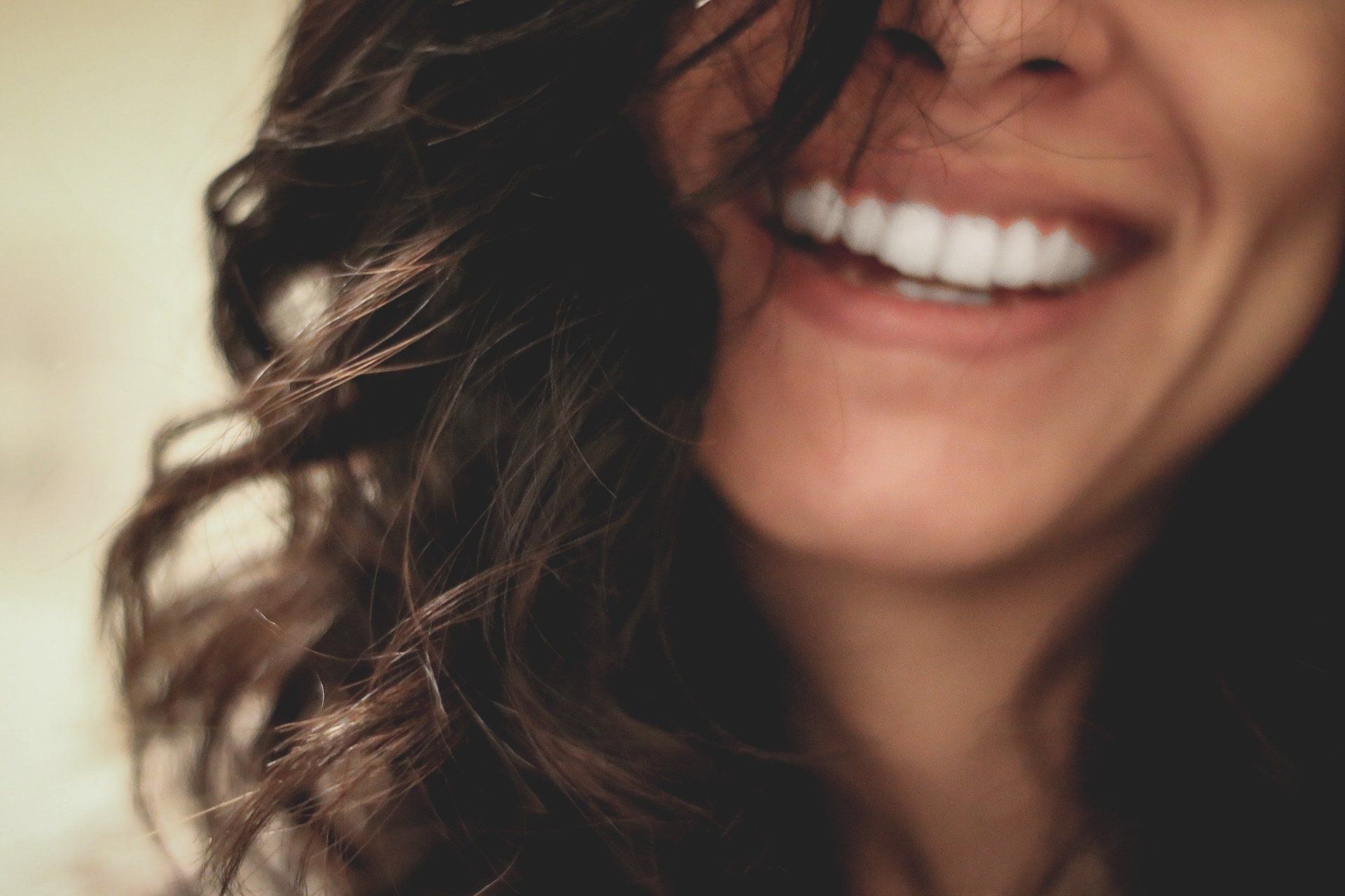 A woman is smiling with her hair blowing in the wind.
