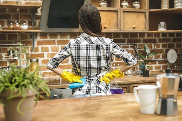 a woman wearing yellow gloves is cleaning a kitchen counter .
