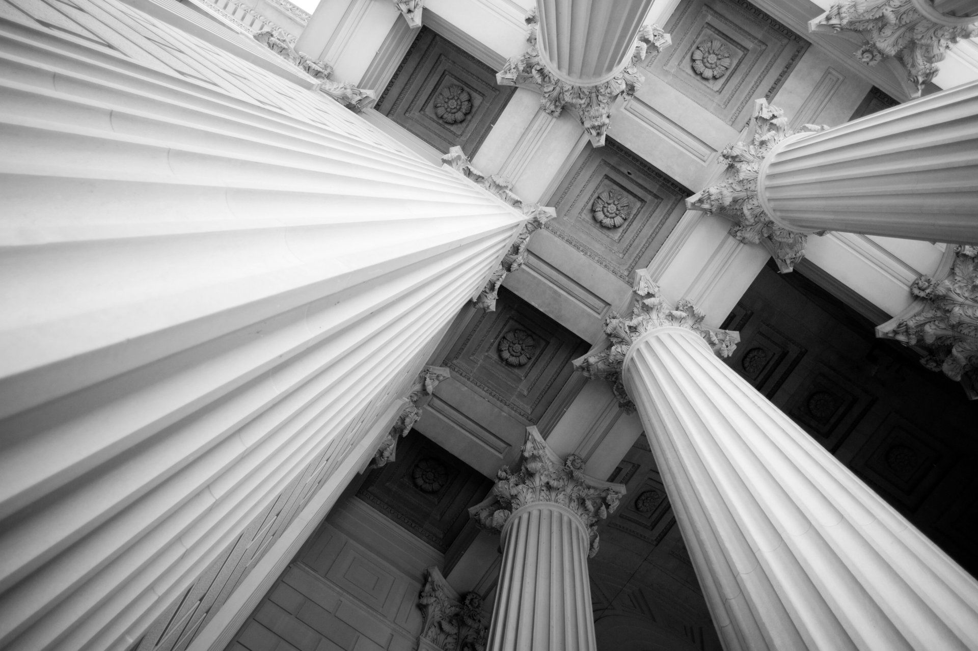 Looking up at the columns of a building in a black and white photo.