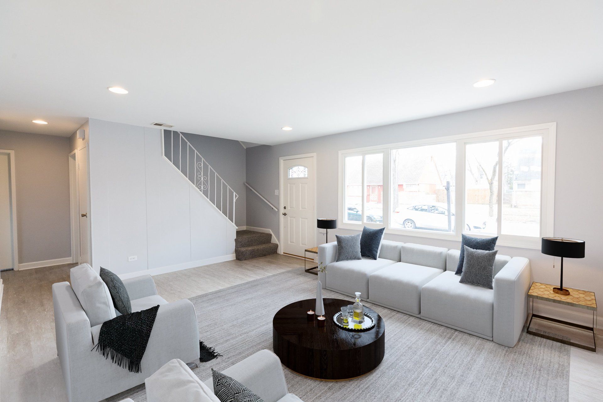 a living room with a couch , chairs , coffee table and stairs .