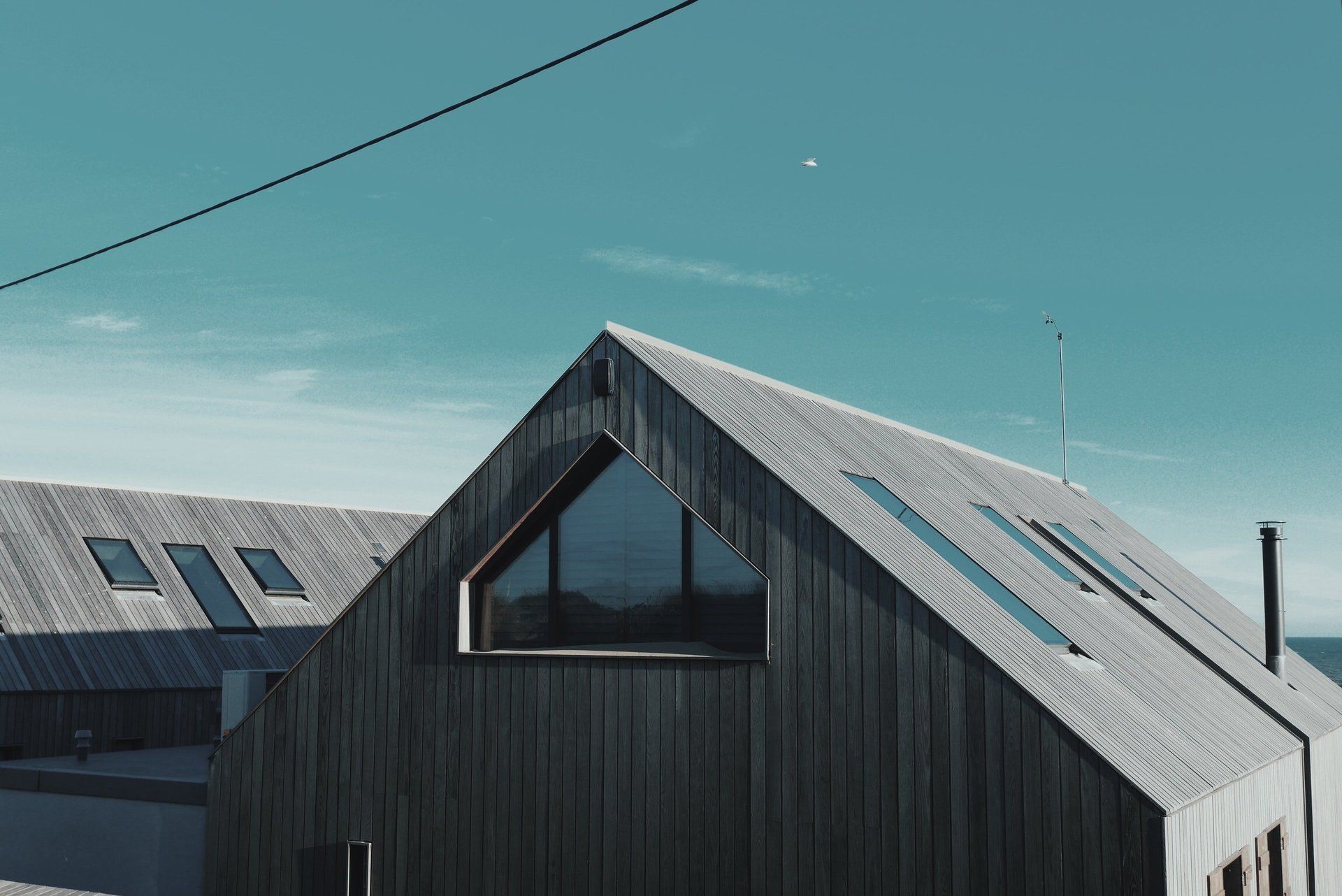 A black house with a triangle shaped roof and a lot of windows.
