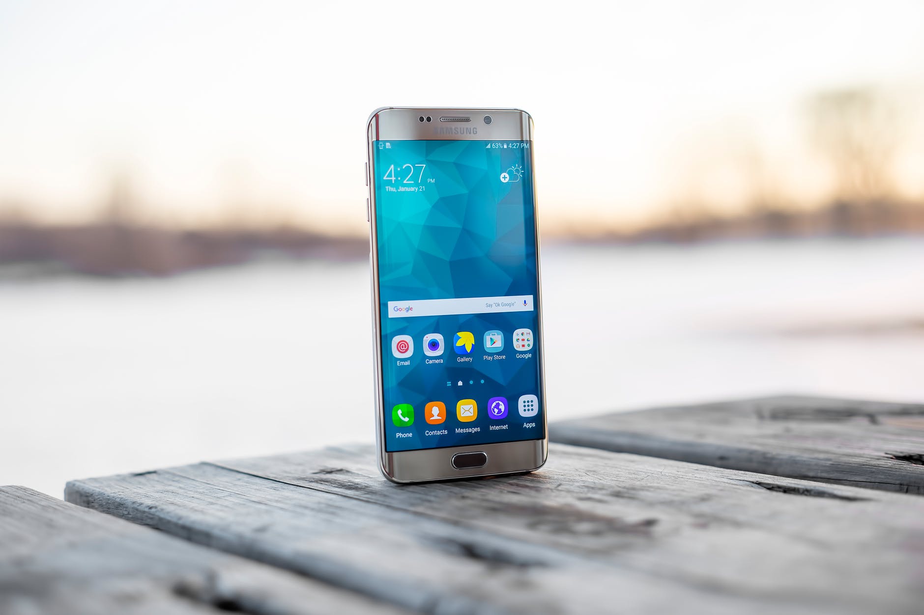 A samsung galaxy s6 edge is sitting on a wooden table.