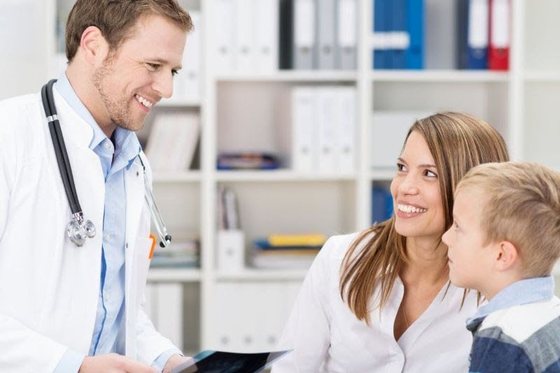 A doctor is talking to a young boy and his mother.