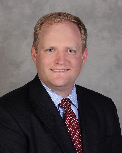 a man in a suit and tie is smiling for the camera