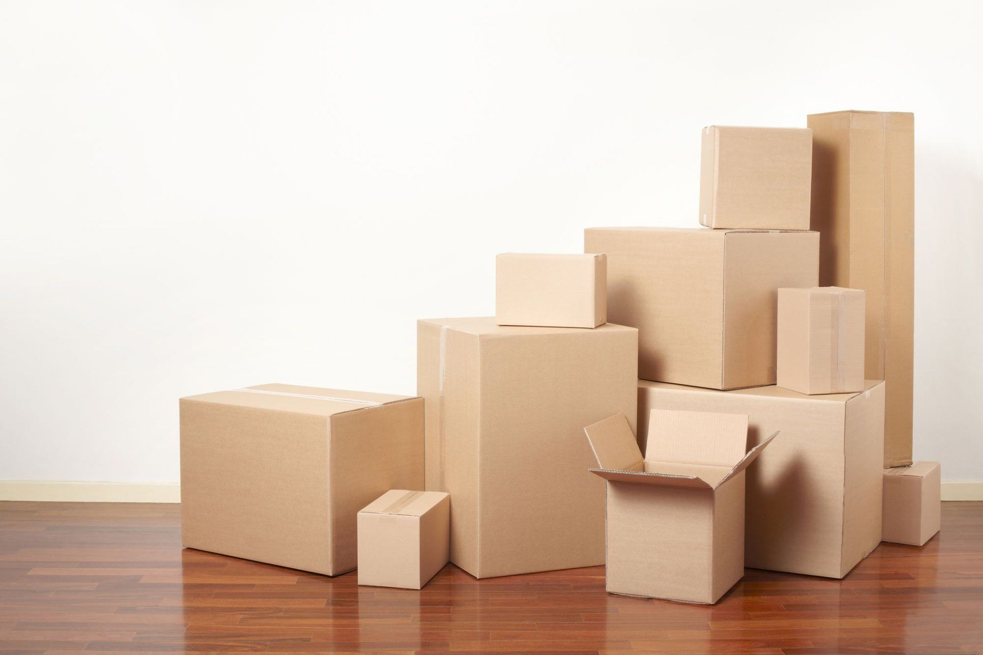 A bunch of cardboard boxes are stacked on top of each other on a wooden floor.