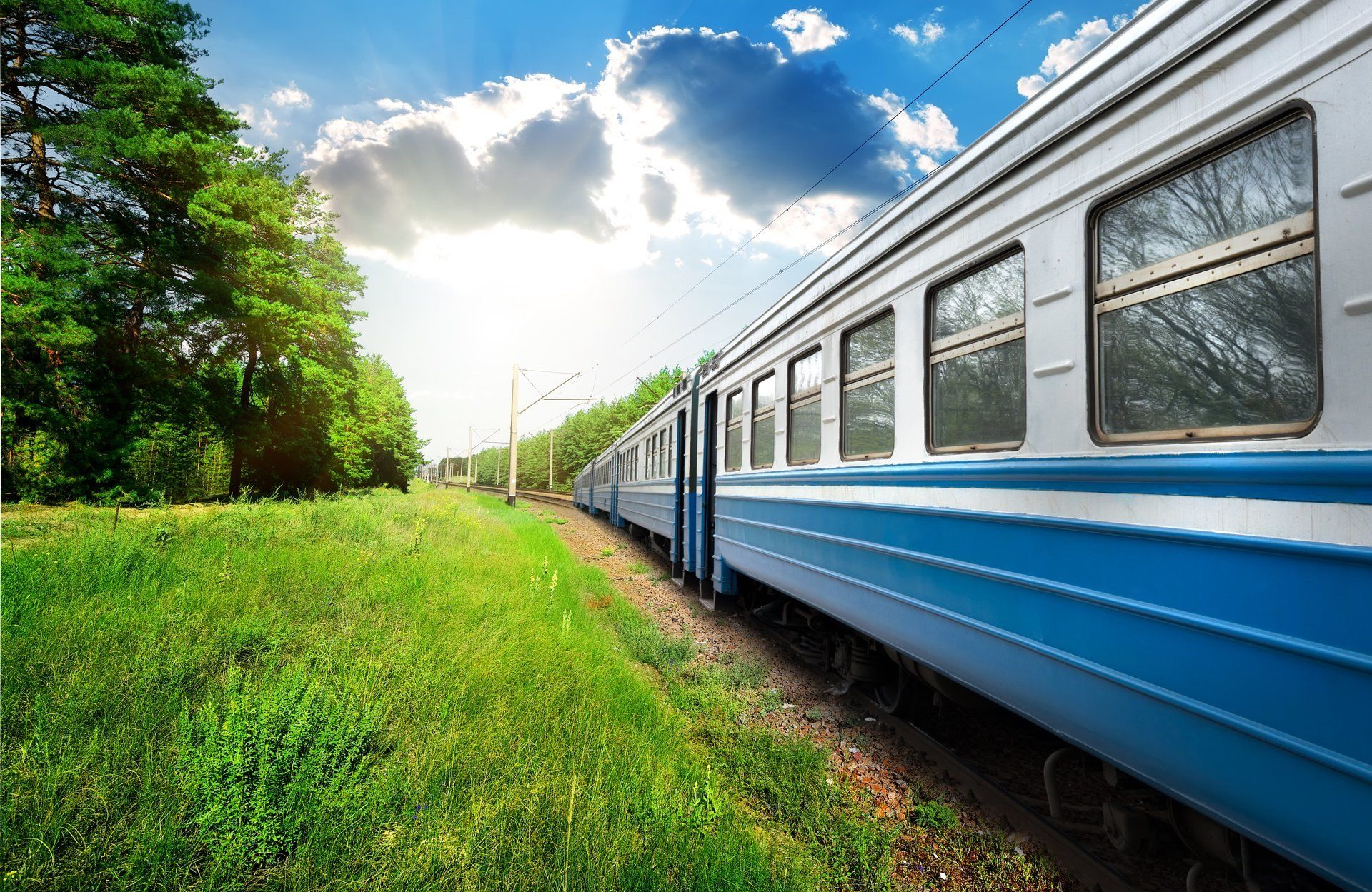 A blue and white train is going down the tracks.