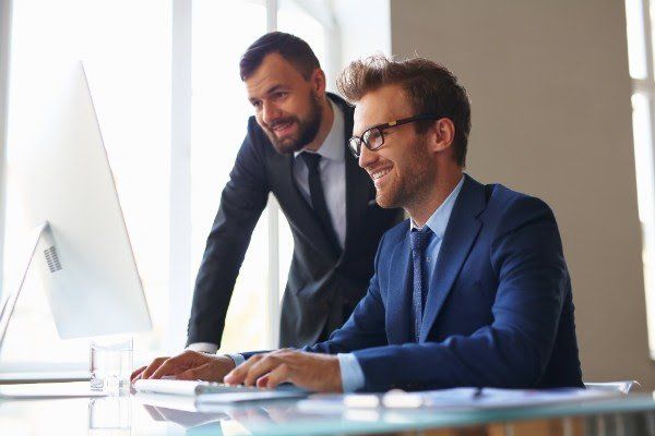 Two men in suits are looking at a computer screen.