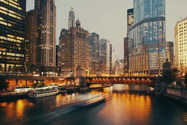 a boat is floating down a river in front of a city skyline at night .