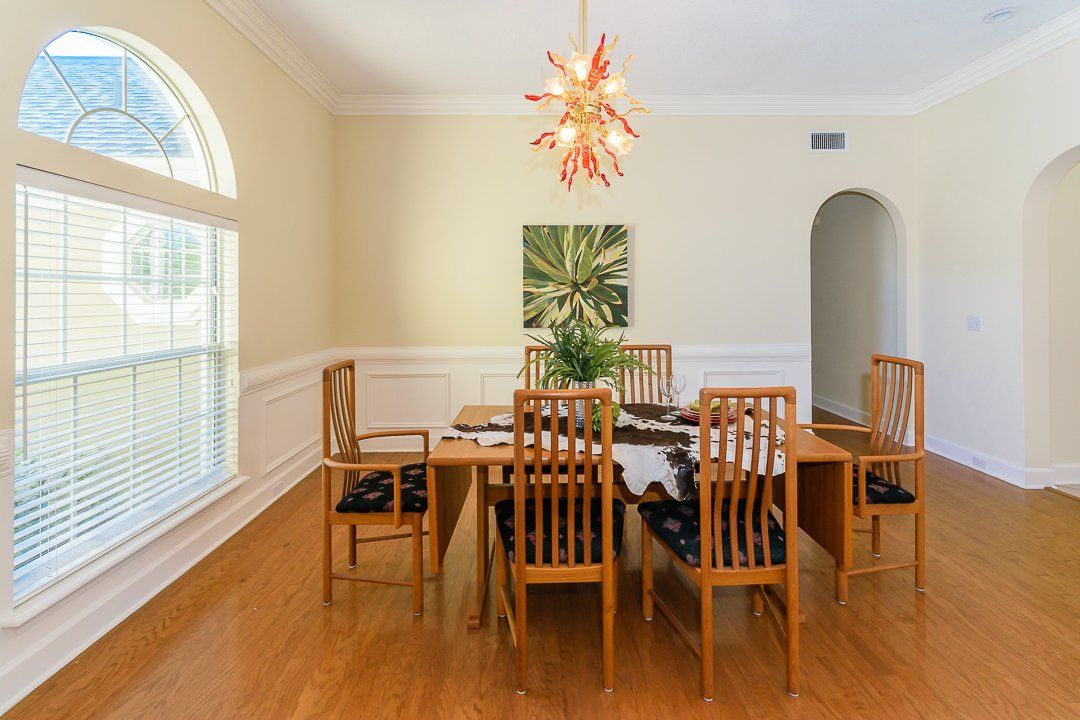 A dining room with a table and chairs and a chandelier hanging from the ceiling.