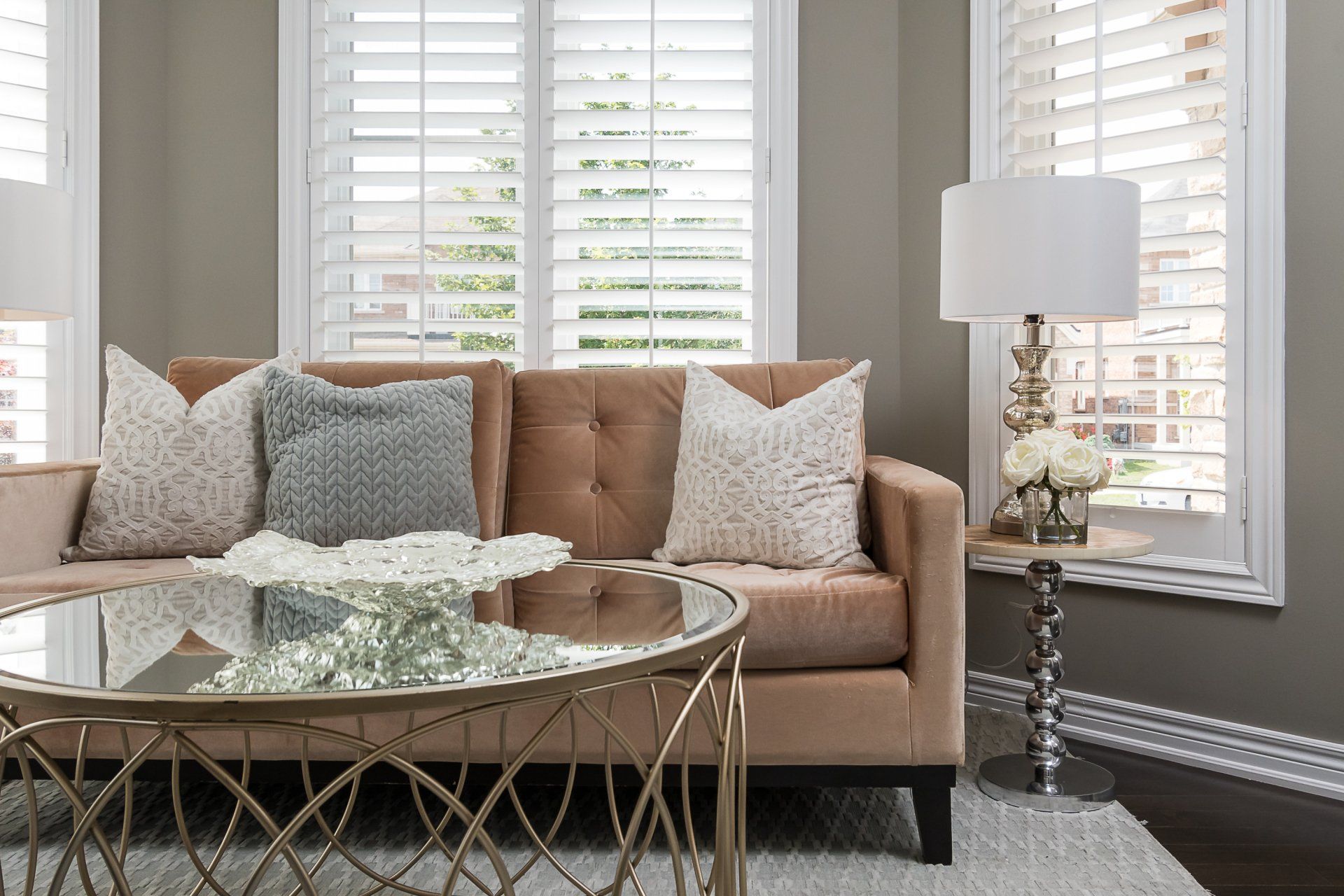 A living room with a couch , coffee table , lamp and shutters.