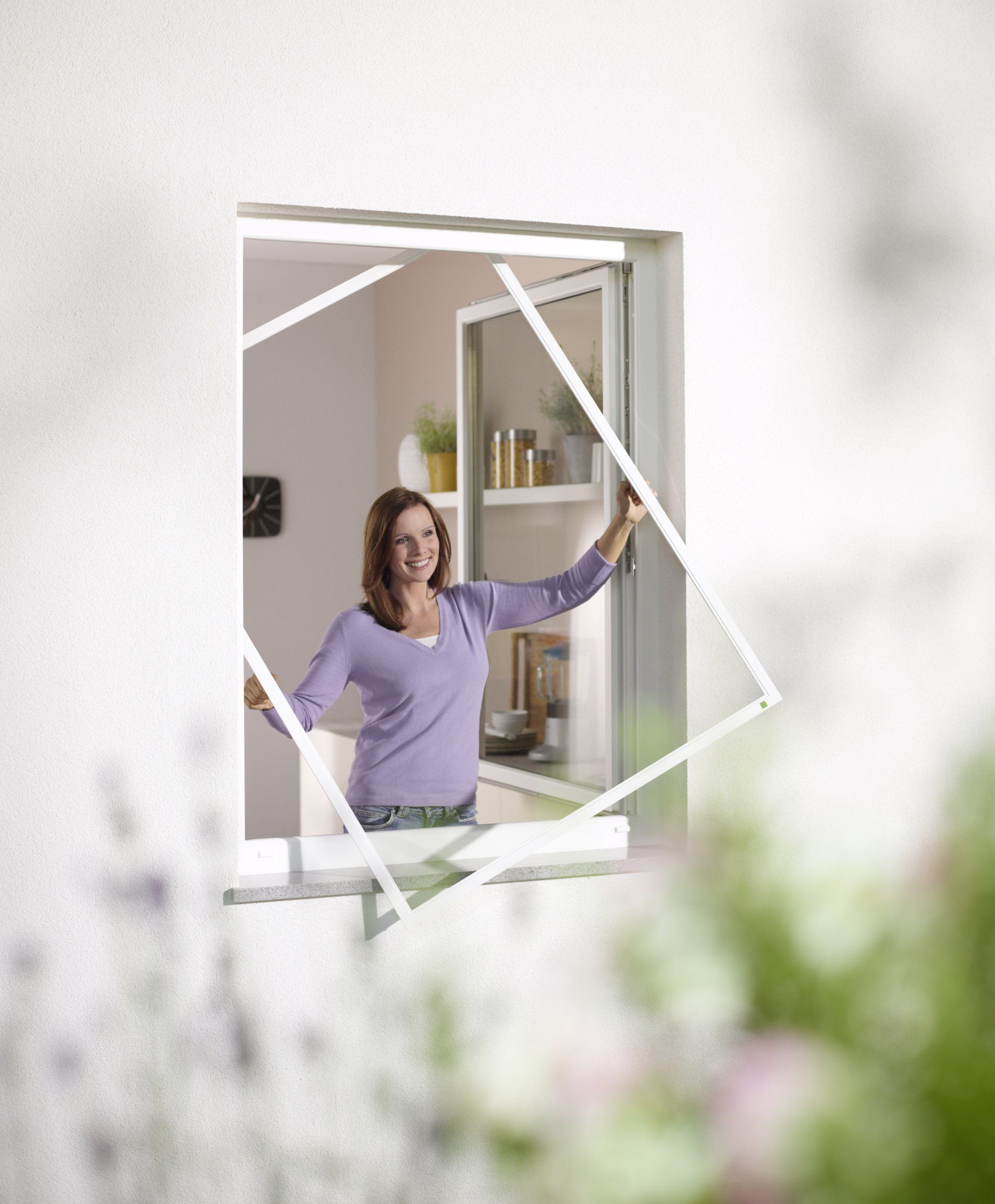 Eine Frau in einem lila Hemd schaut aus einem Fenster