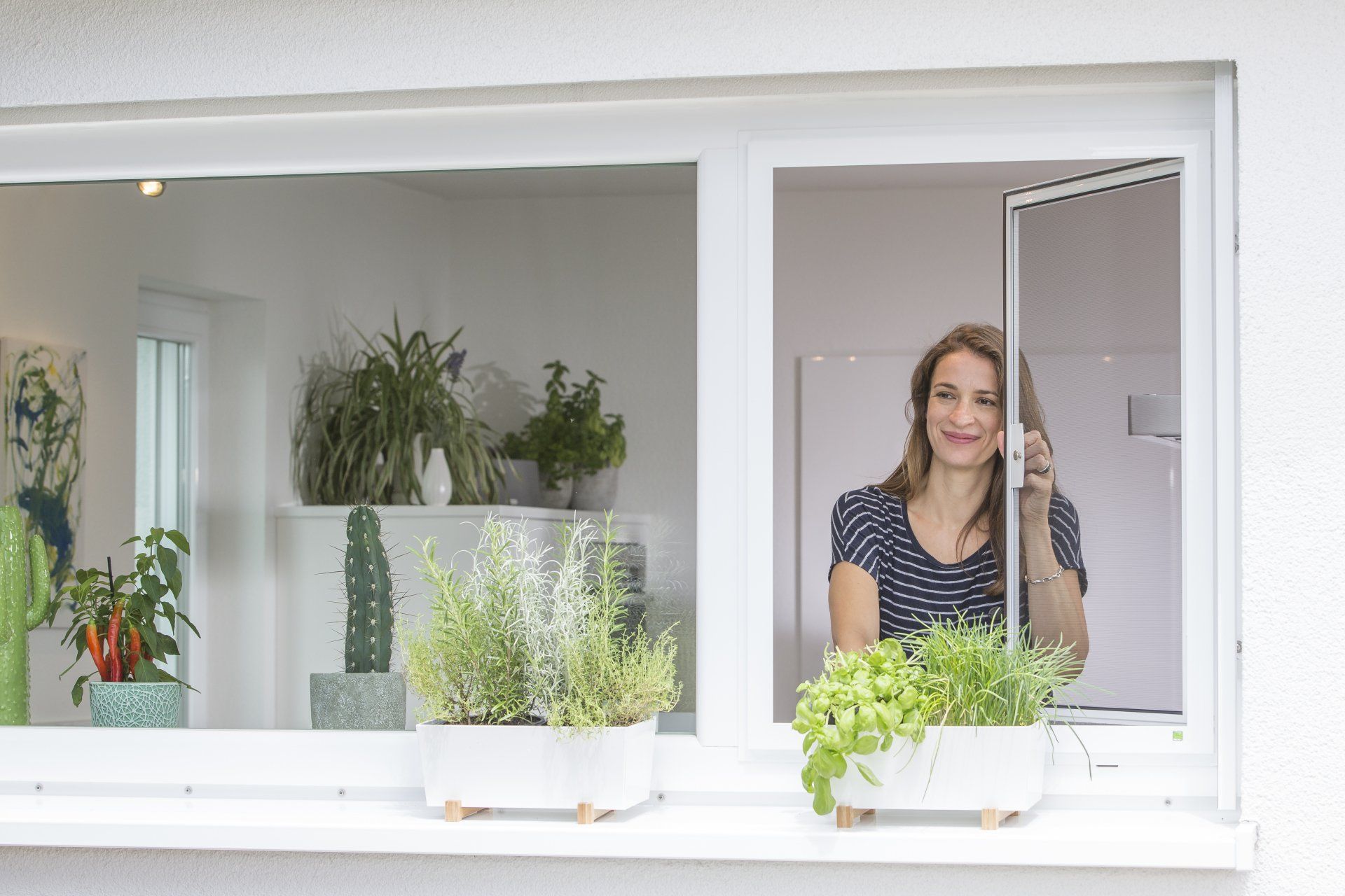 Eine Frau schaut aus dem Fenster und telefoniert dabei mit einem Mobiltelefon.