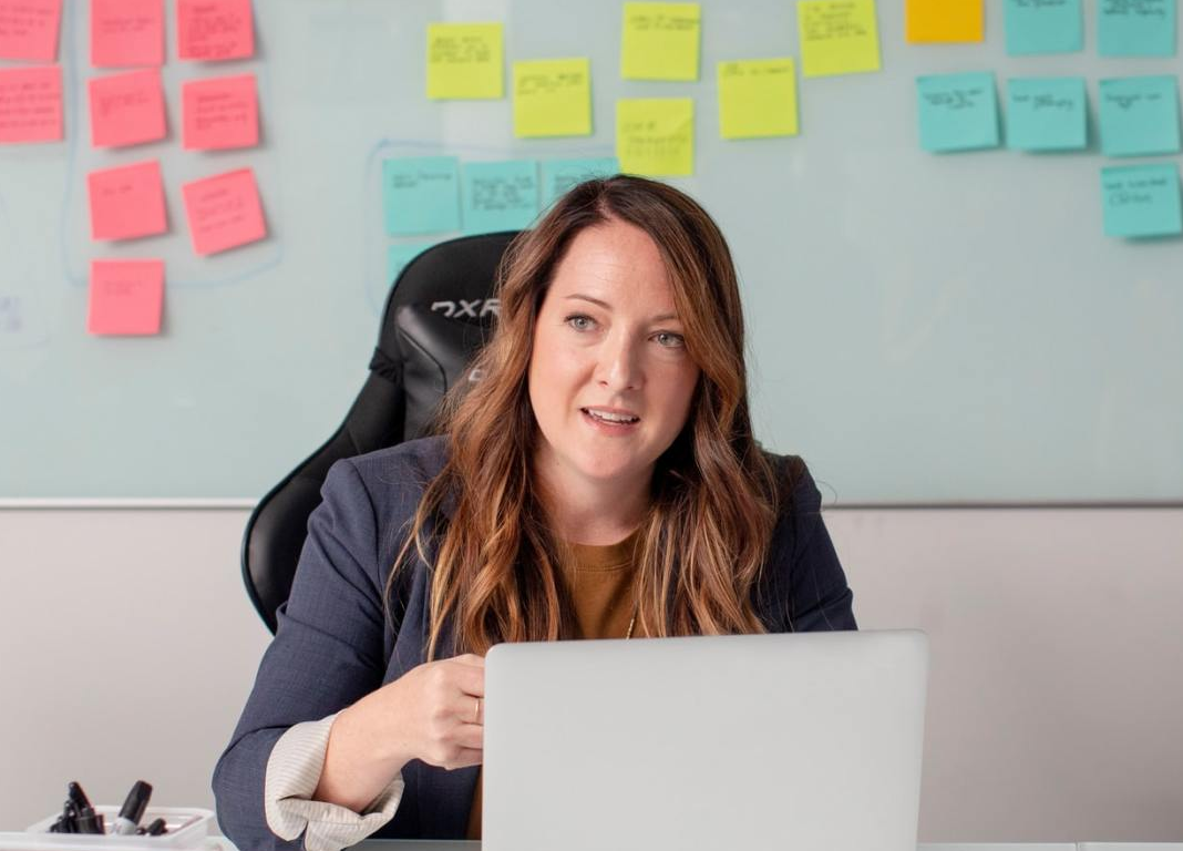 A woman is sitting at a desk in front of a laptop computer.