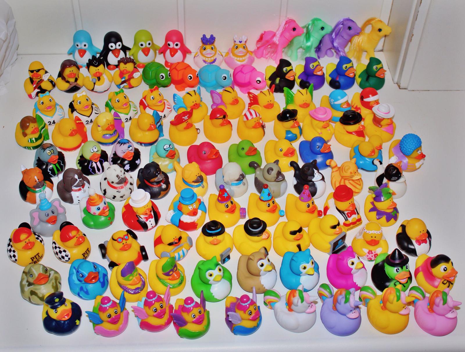 Een grote verzameling kleurrijke badeendjes met verschillende ontwerpen, die bij elkaar op een witte ondergrond zijn uitgestald.