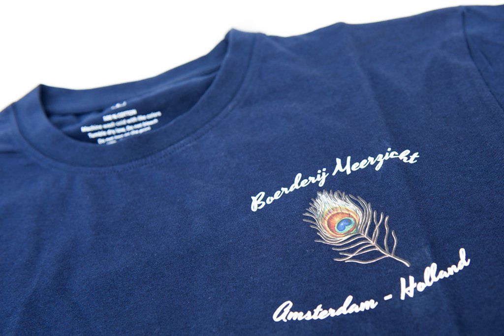 Donkerblauw T-shirt met geborduurde pauwenveer en de tekst 
