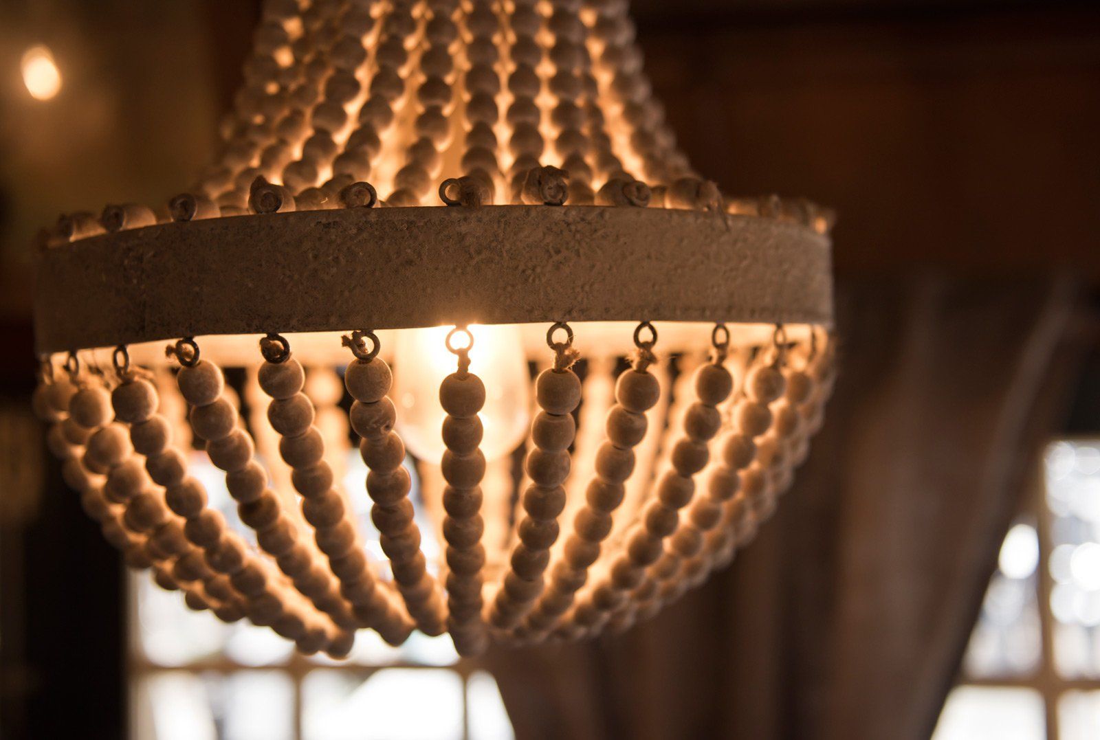 Houten kroonluchter met kralen die warm licht uitstraalt, interieurdecoratie.