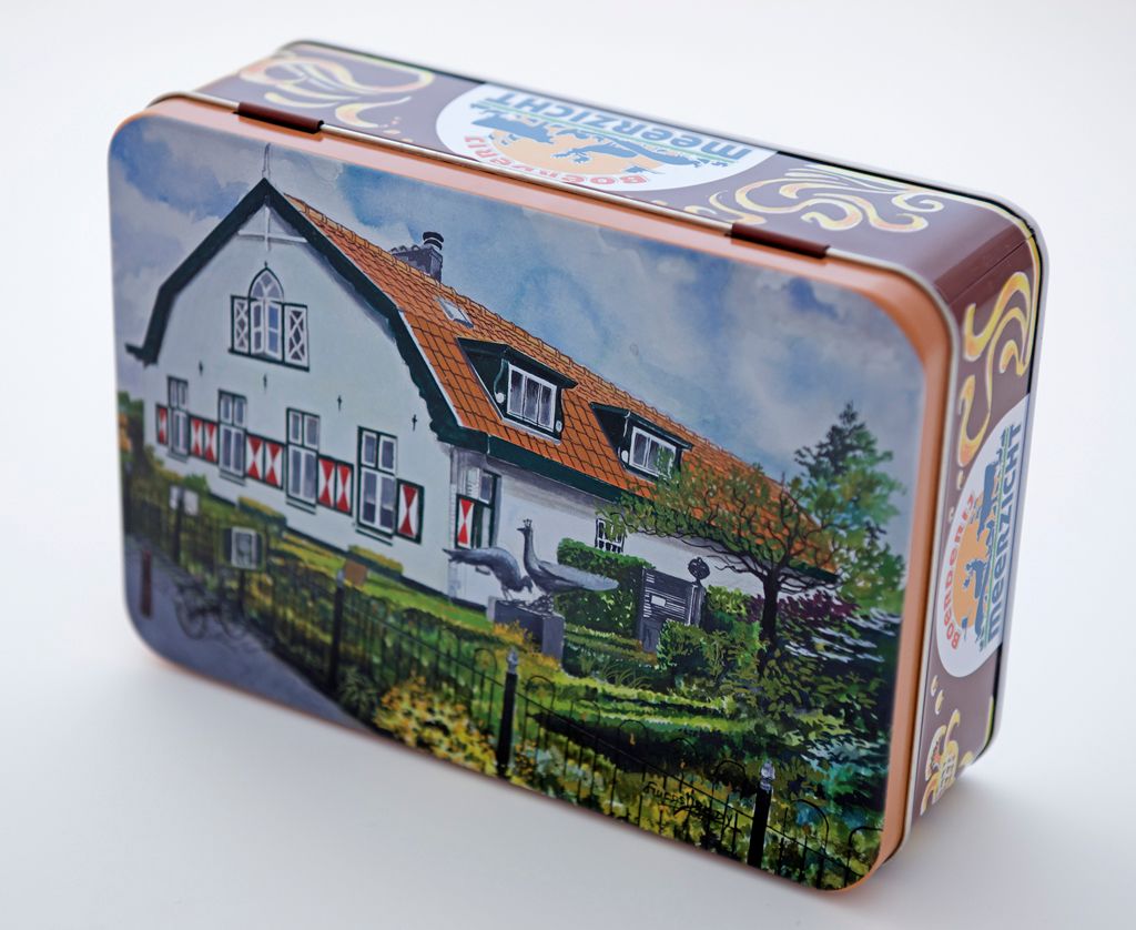 Een blikken doos met een geschilderde afbeelding van een wit huis met een rood dak, in een grasrijke omgeving.