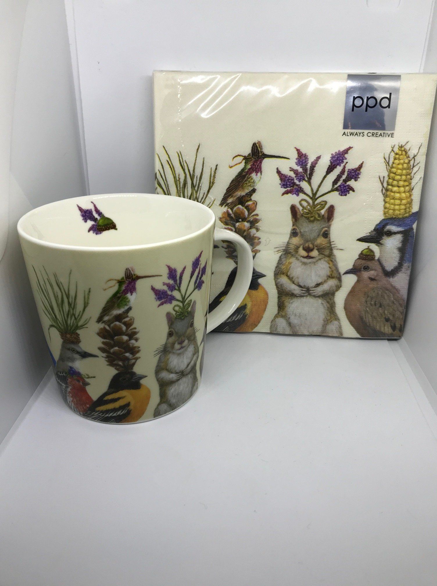 Mok en servetten versierd met afbeeldingen van dieren, planten en kleurrijke details op een witte achtergrond.
