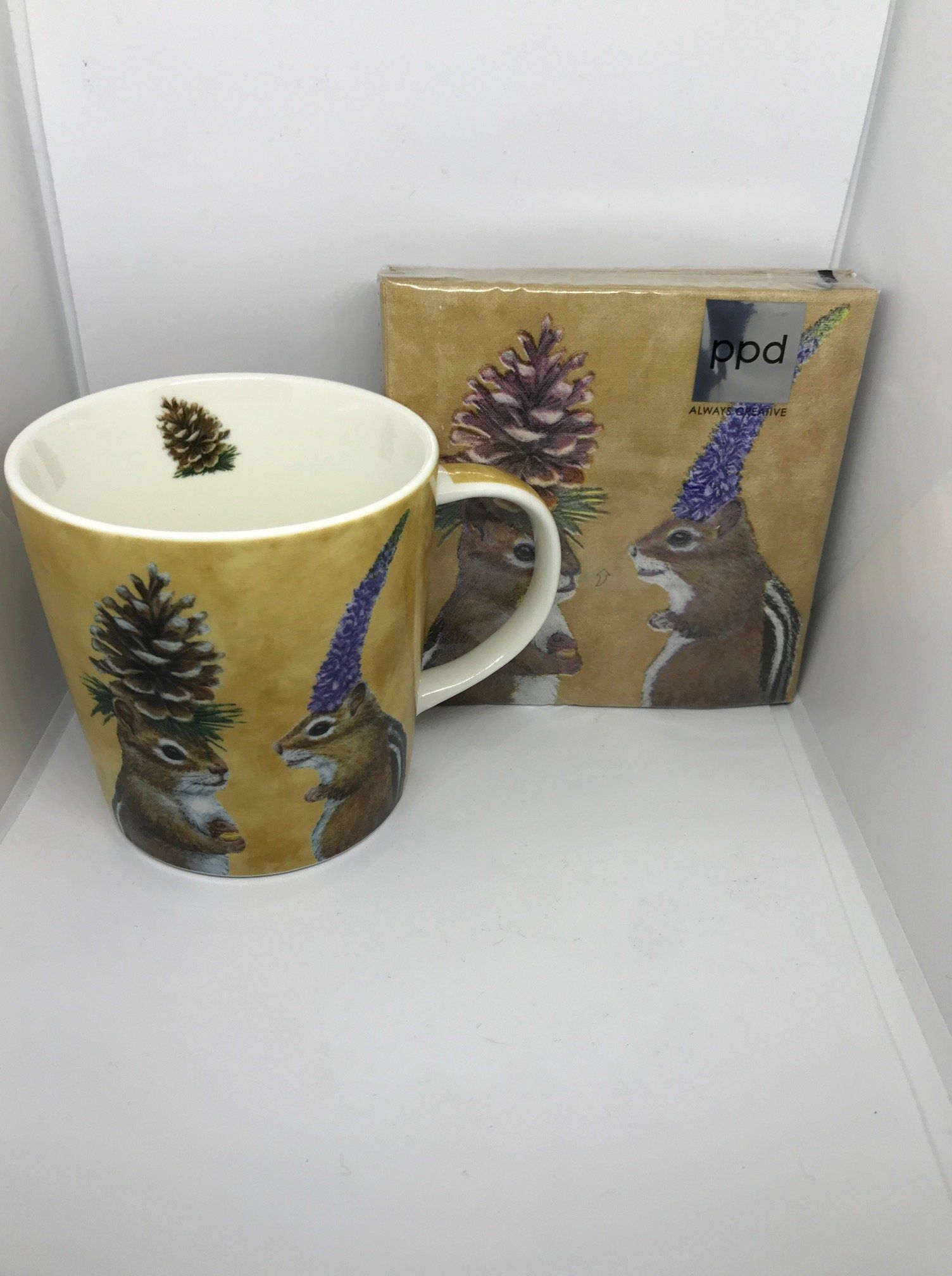 Mok en doos met eekhoornmotief, beige achtergrond, dennenappels en eekhoorns.