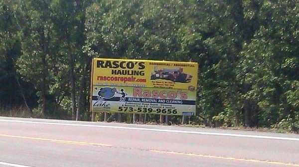 a billboard for rasco 's hauling is on the side of the road