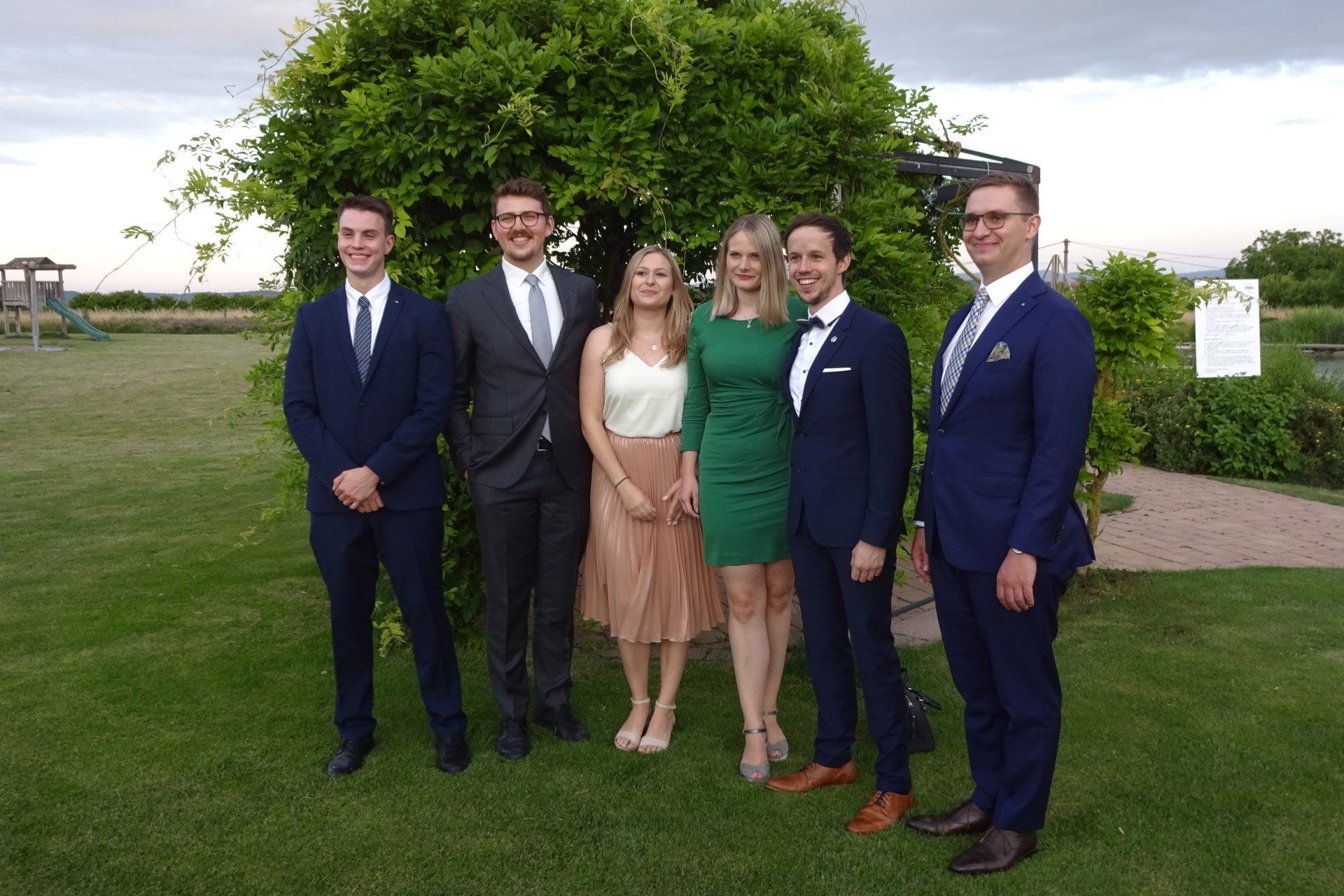 Eine Gruppe von Menschen posiert für ein Foto vor einem Baum.