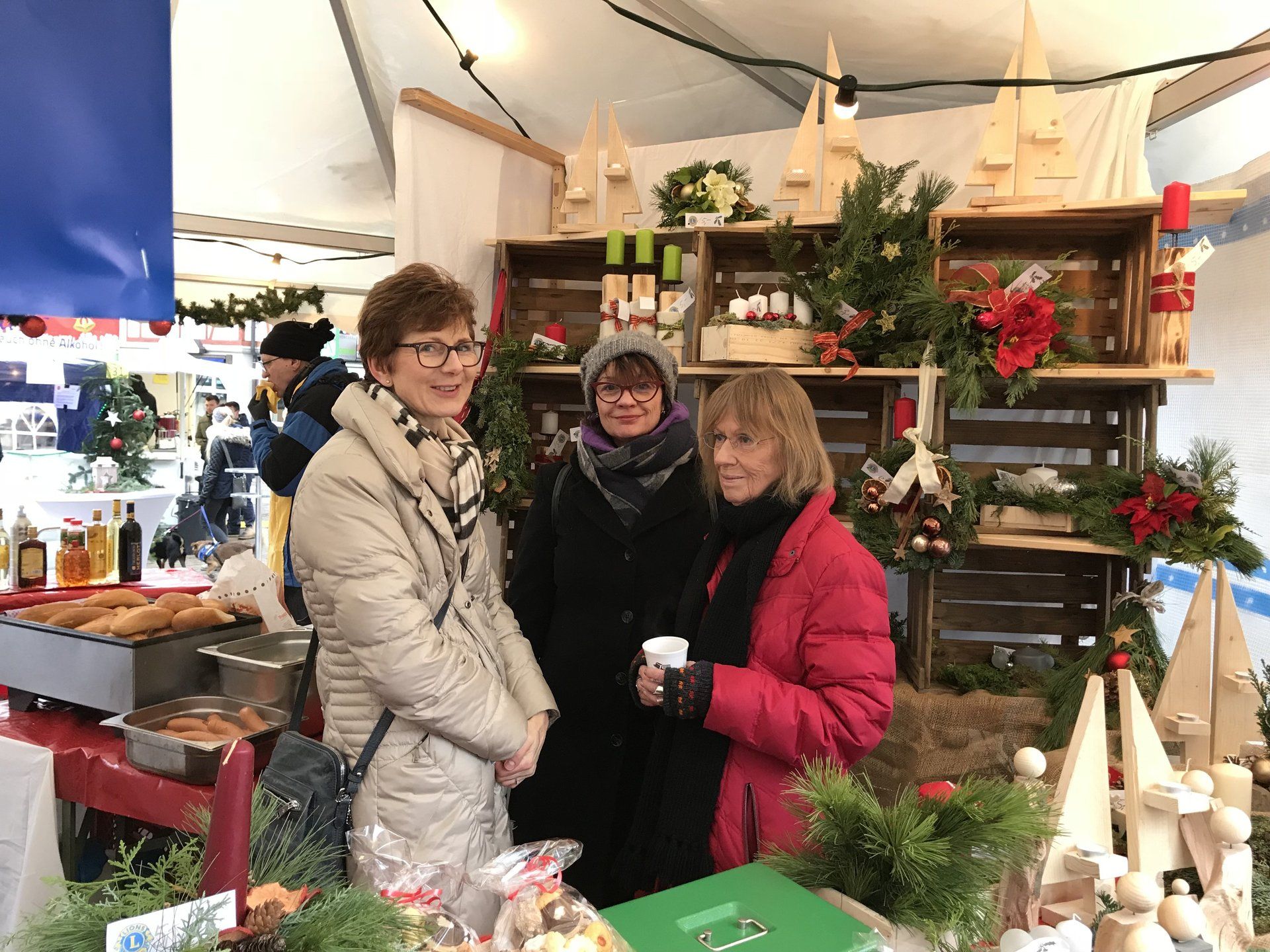 Drei Frauen stehen nebeneinander auf einem Weihnachtsmarkt.
