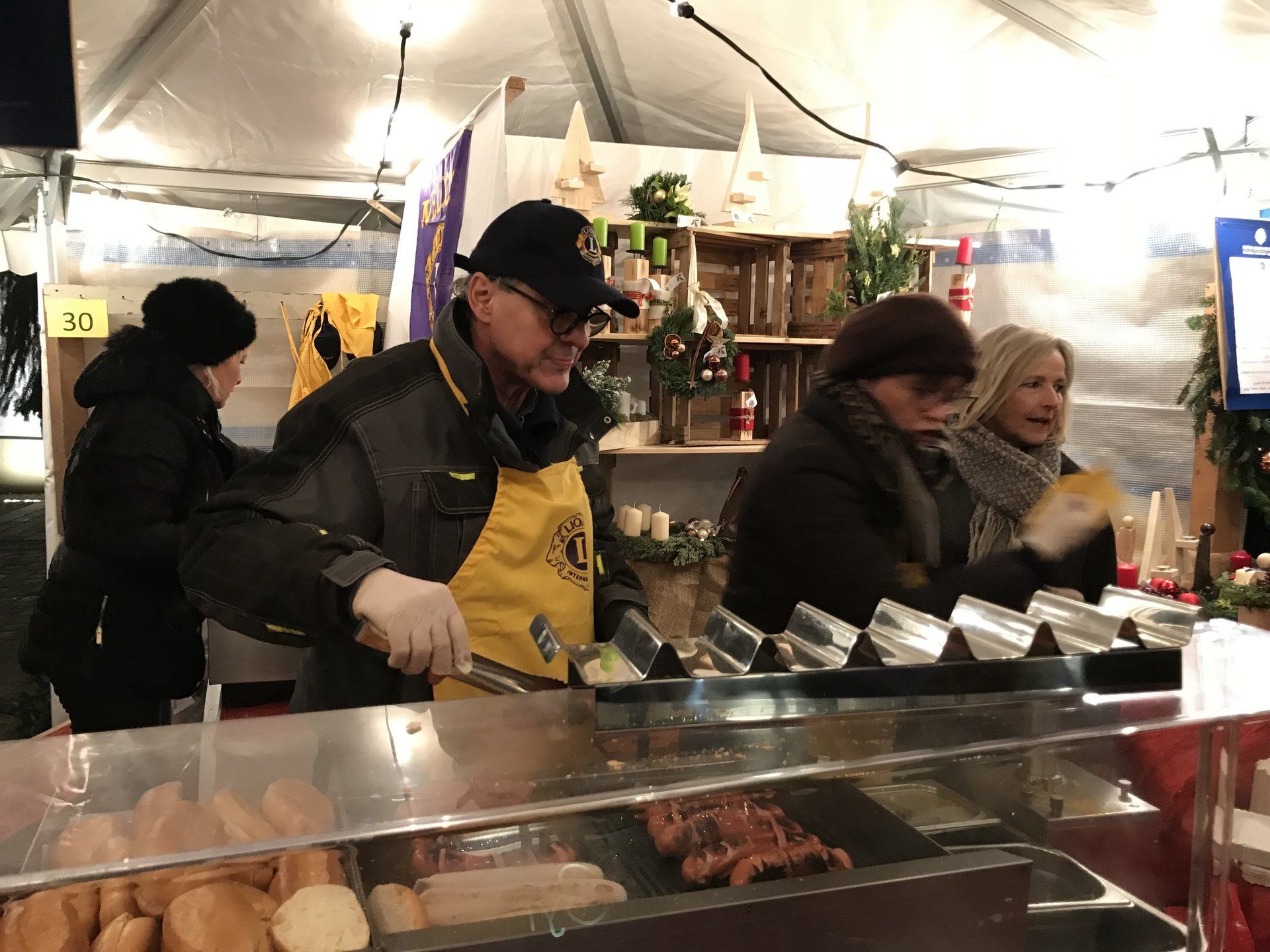 Ein Mann in einer gelben Schürze kocht Essen auf einem Markt.