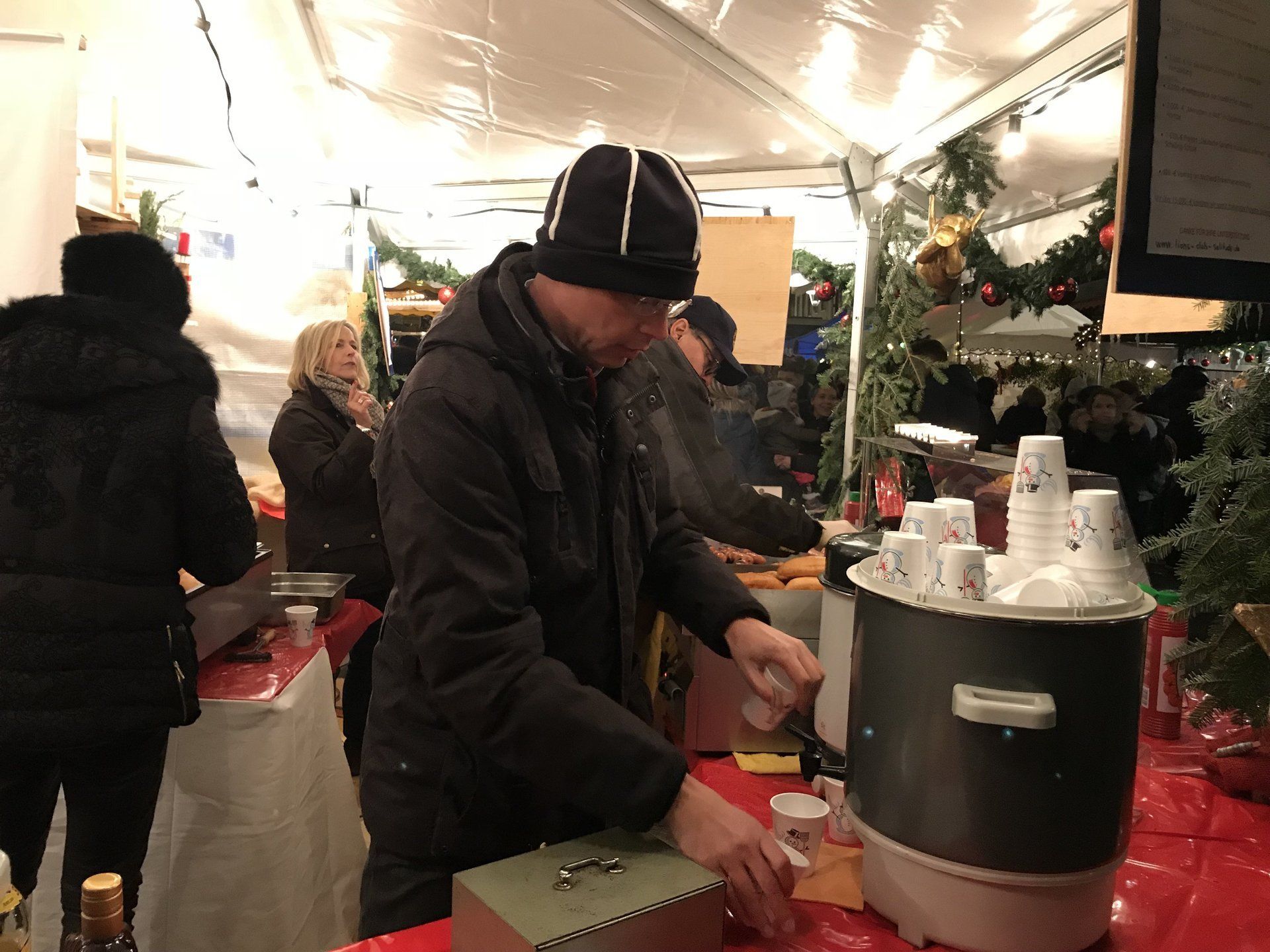 Auf einem Weihnachtsmarkt kocht ein Mann Essen in einem Topf.