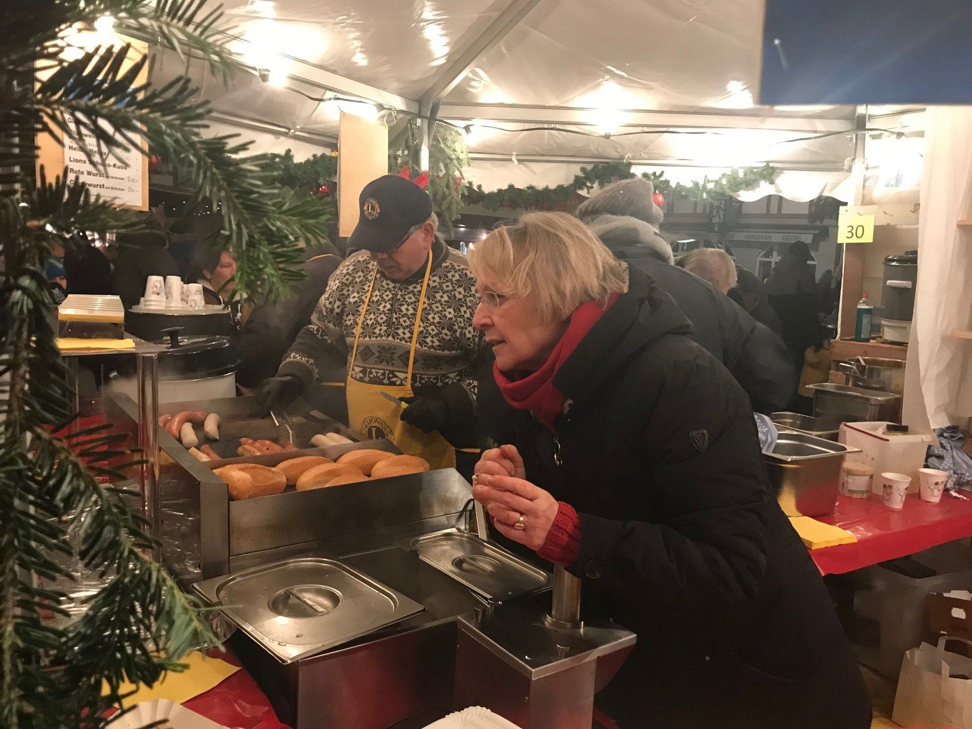 Eine Frau isst Hot Dogs an einem Imbissstand.