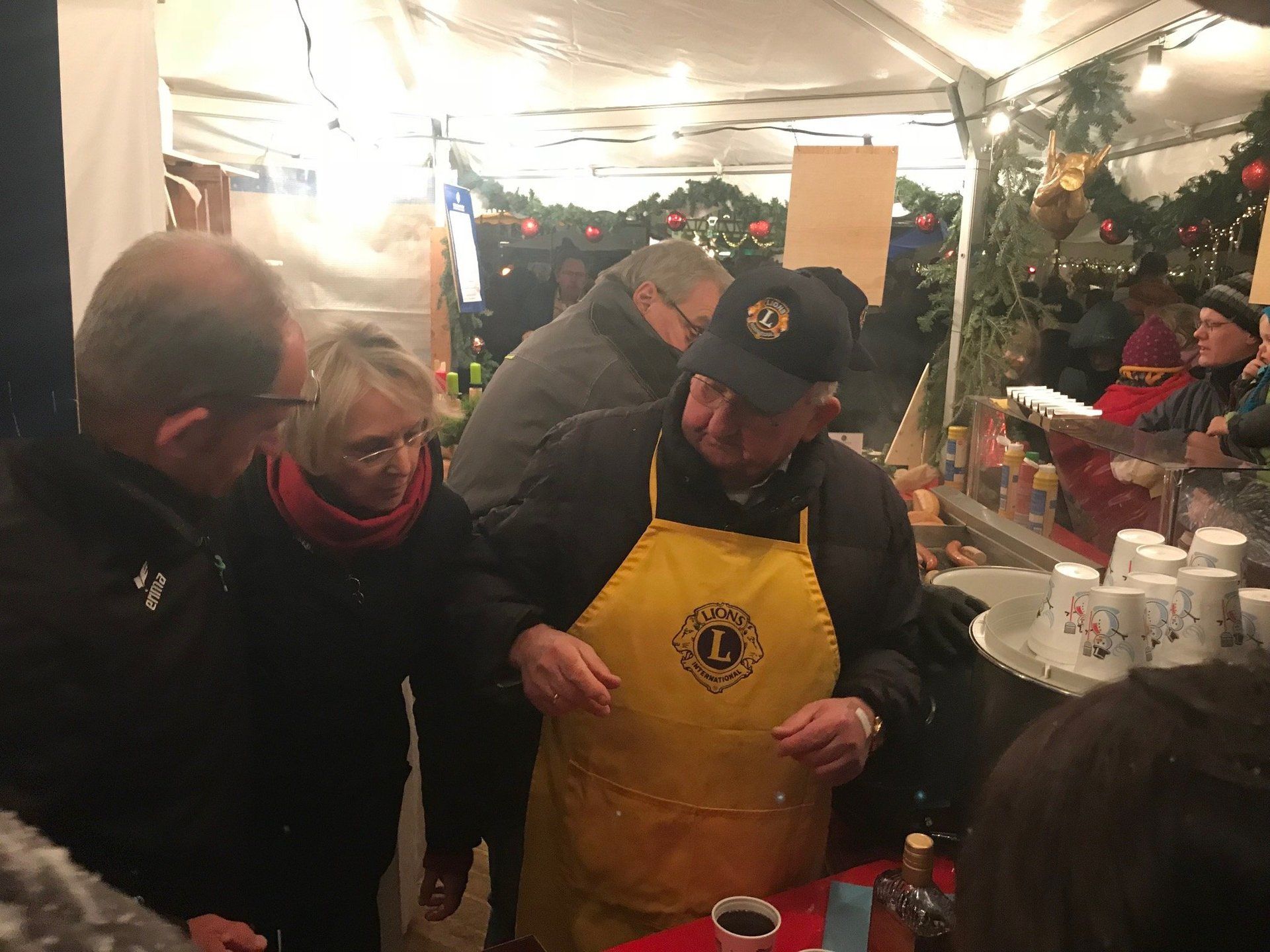 Eine Gruppe von Leuten steht um einen Tisch herum , ein Mann trägt eine gelbe Schürze.