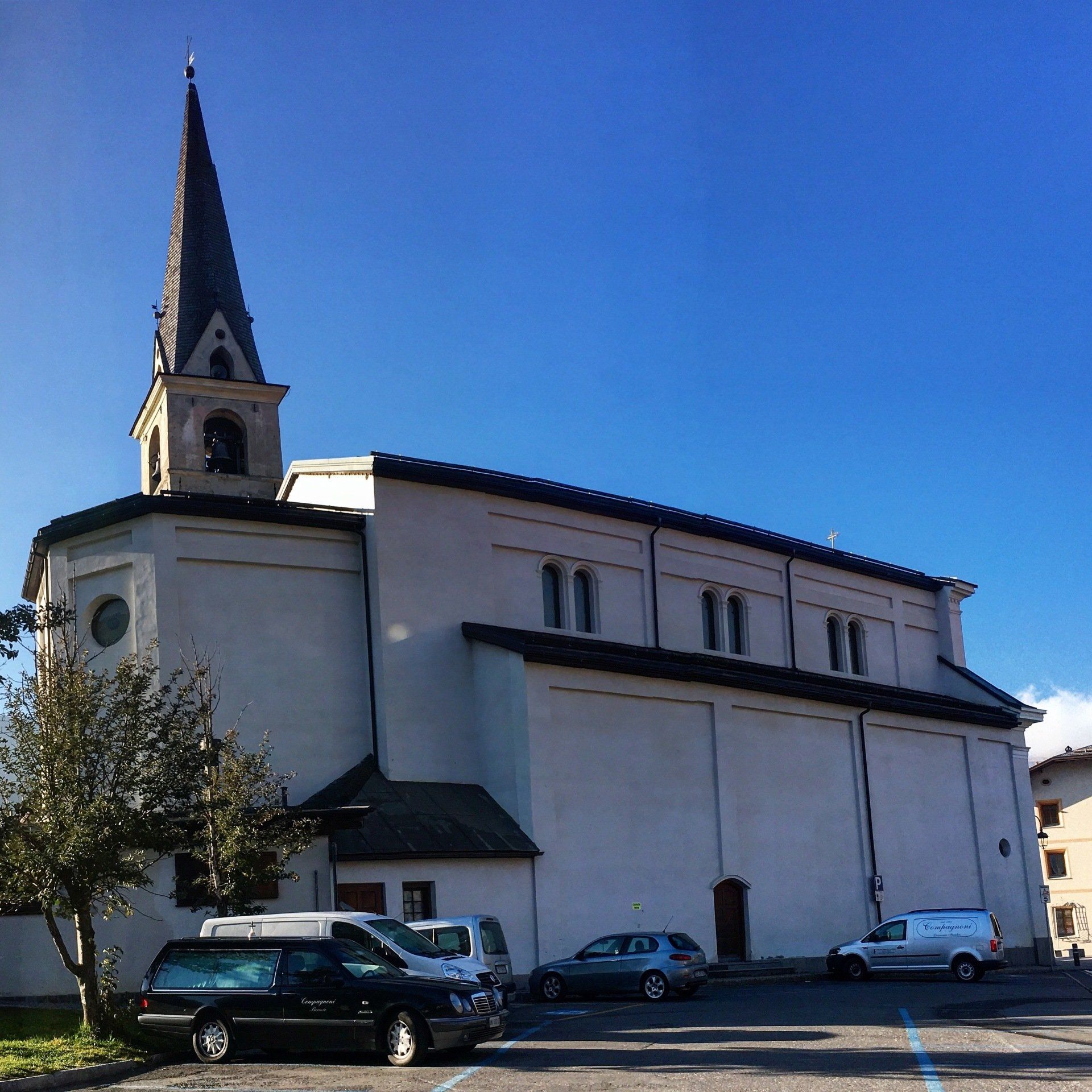 Una chiesa con un campanile e delle auto parcheggiate davanti