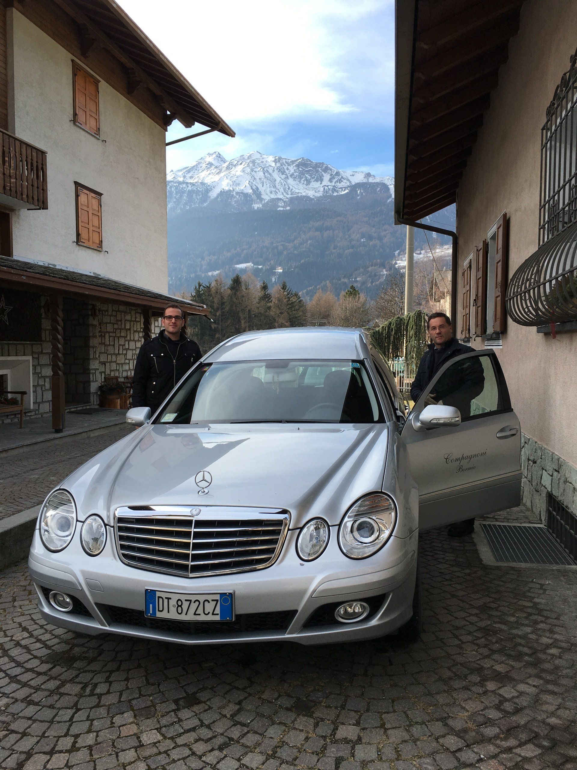 Una mercedes argentata è parcheggiata davanti a un edificio