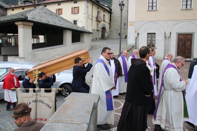 Un gruppo di sacerdoti che trasportano una bara davanti a un edificio