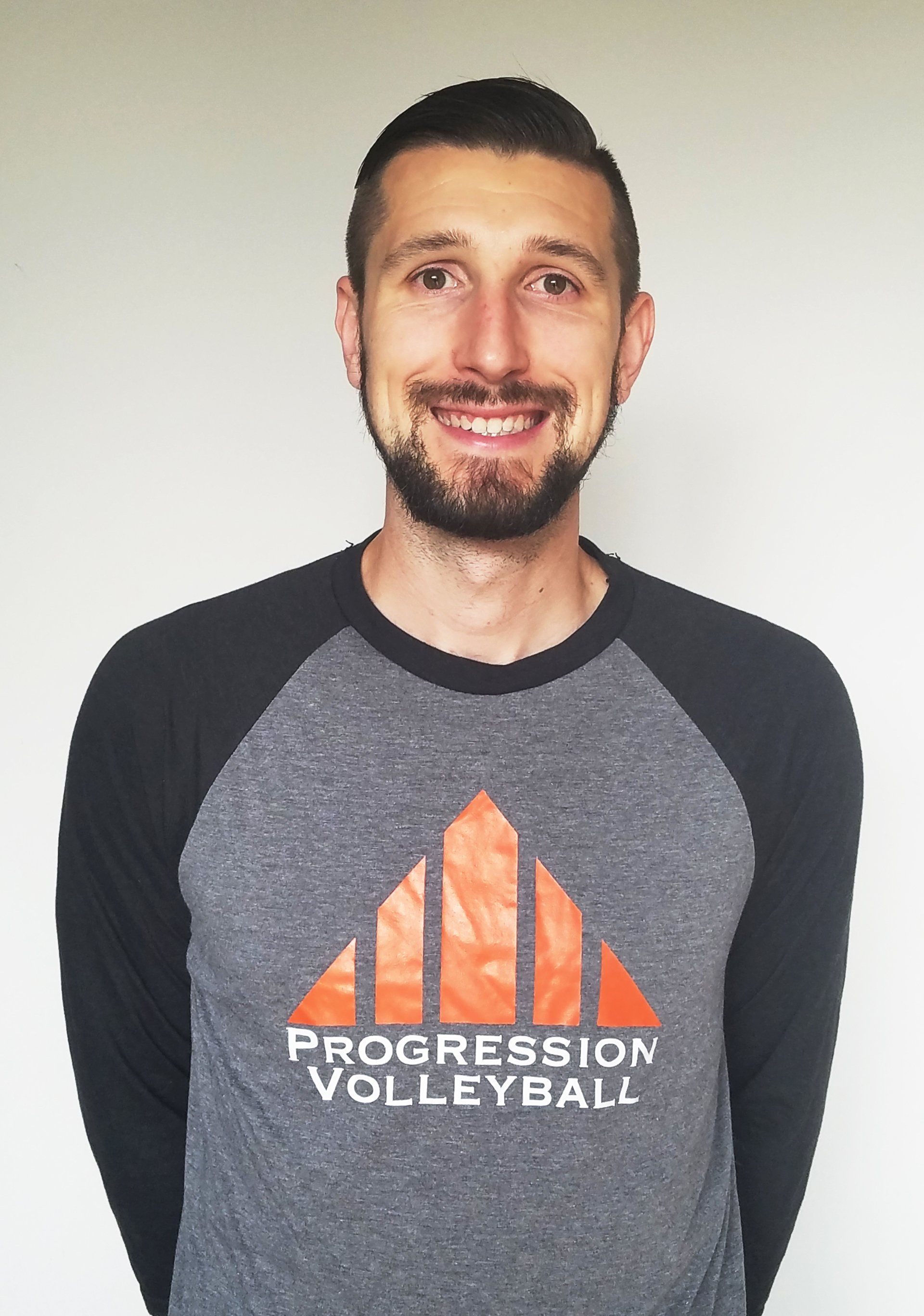 A man is wearing a shirt that says progression volleyball