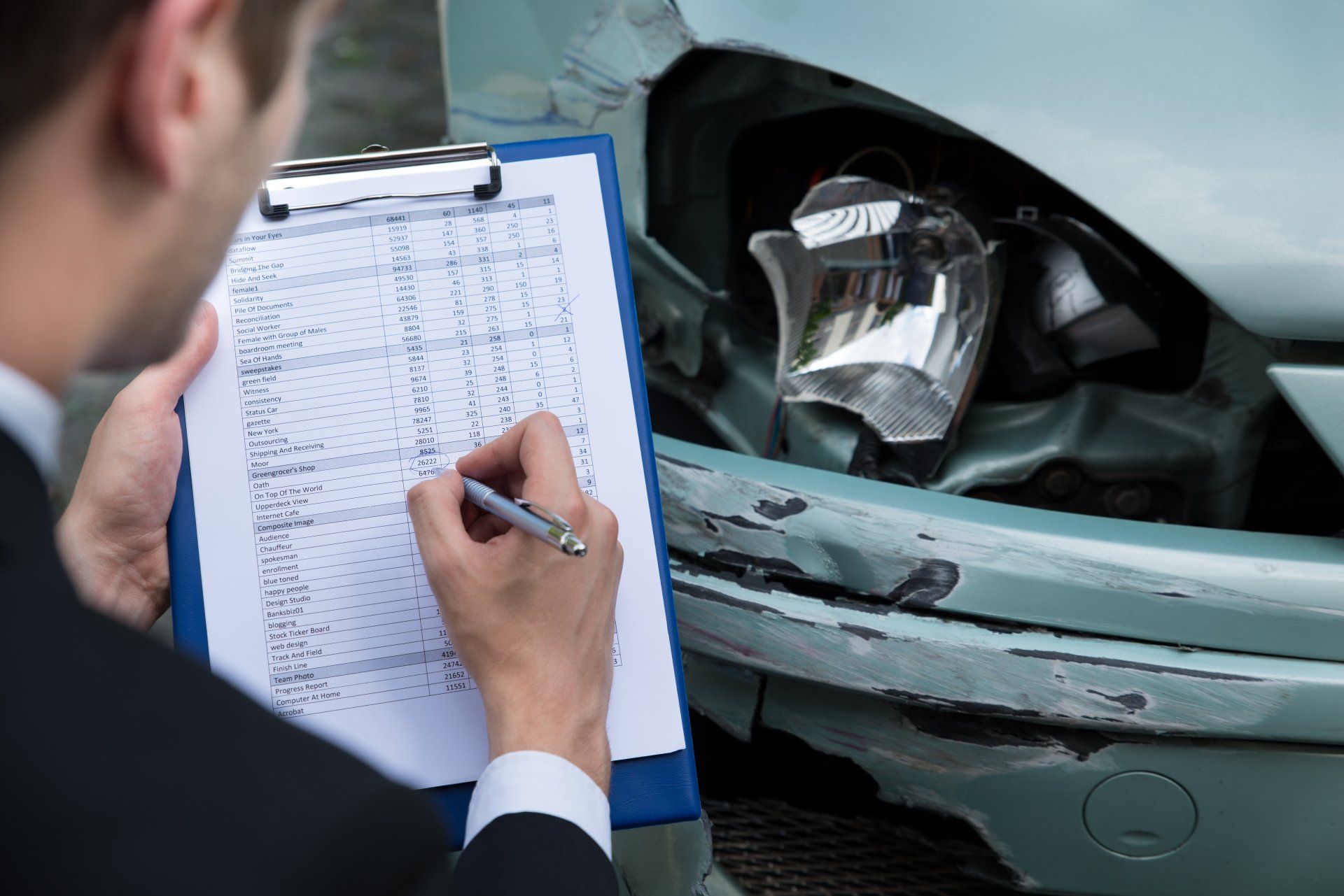 Ein Versicherungssachverständiger untersucht nach einem Unfall den Schaden an der Frontpartie eines Autos.