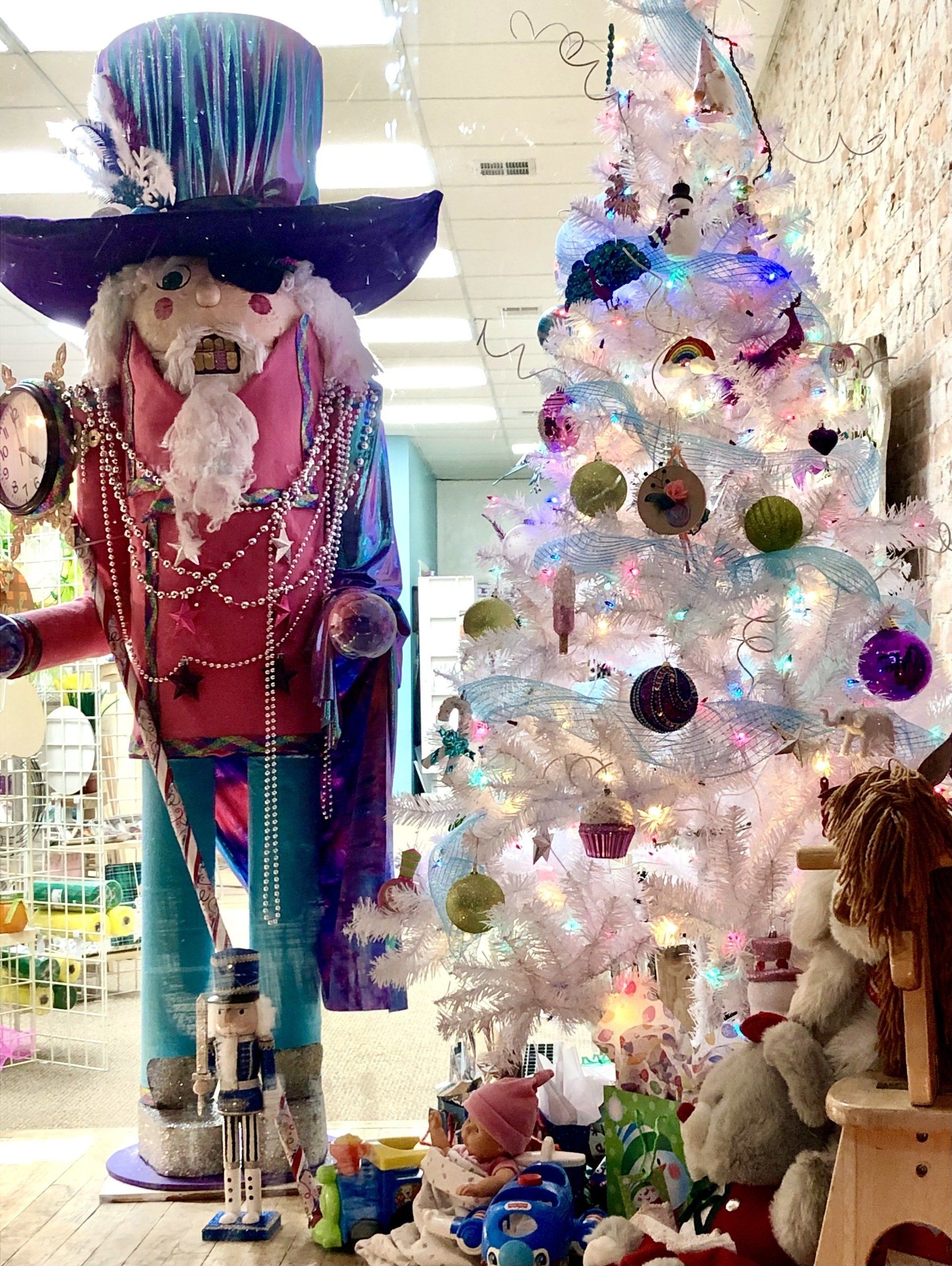 A giant nutcracker is standing next to a white christmas tree.