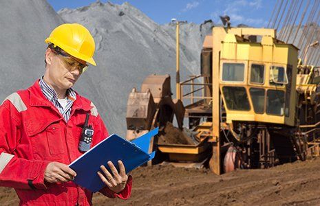 A foreman in a mining site, checking the logs in a blue folder A foreman in a mining site, checking the logs in a blue folder