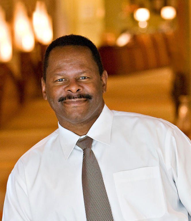 A man in a white shirt and tie smiles for the camera