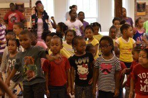 A group of children are standing in a room and one of them has a hello kitty shirt on