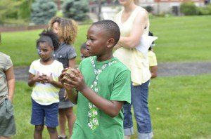 A boy in a green shirt is standing in front of a group of children.