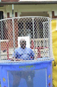 A man is sitting in a water bucket behind a fence.