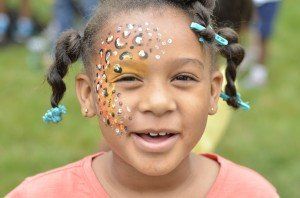A little girl with her face painted like a leopard.