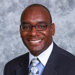 A man in a suit and tie is smiling for the camera.