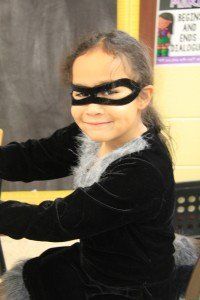 A little girl wearing a mask and a cat costume