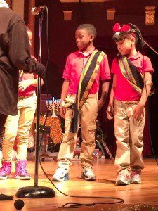 A group of young boys are standing in front of a microphone on a stage.