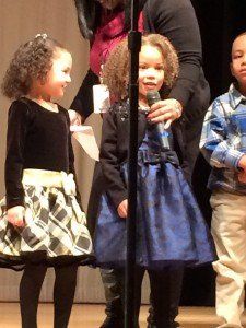 A woman is holding a microphone in front of two little girls