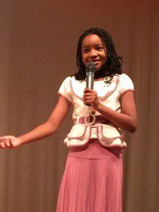 A girl in a pink skirt is holding a microphone