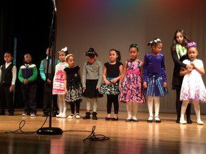 A group of children are standing in front of a microphone on a stage.