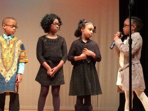 A group of children are standing in front of a microphone on a stage