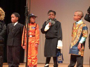 A group of children are standing in front of a microphone